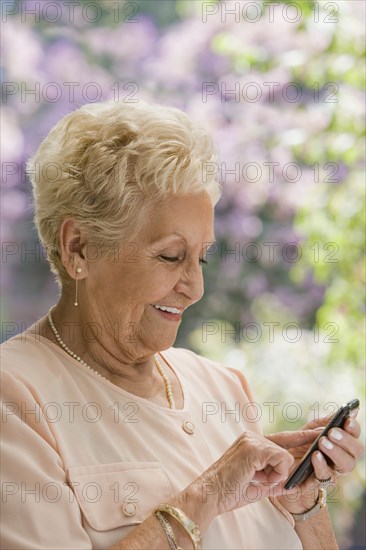 Senior Hispanic woman text messaging on cell phone