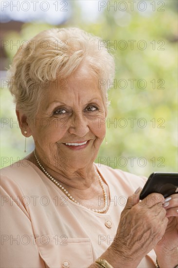 Senior Hispanic woman text messaging on cell phone