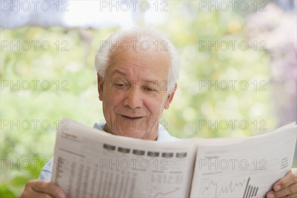 Senior Hispanic man reading financial newspaper