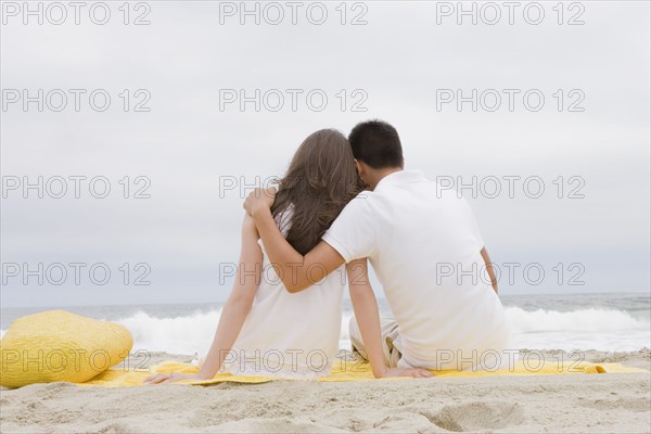 Hispanic couple sitting on beach together