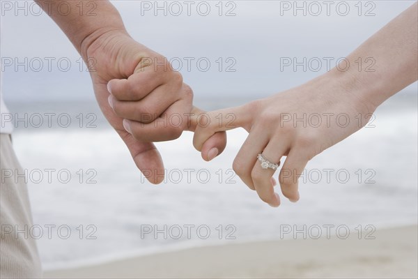 Hispanic couple holding hands on beach