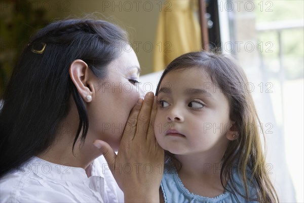 Hispanic mother whispering to daughter