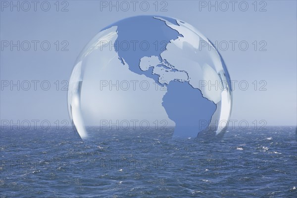 Transparent globe floating on ocean