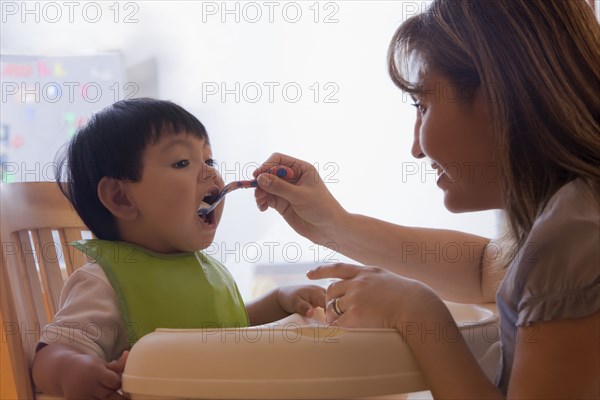 Hispanic mother feeding baby boy