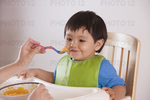 Hispanic mother feeding baby boy