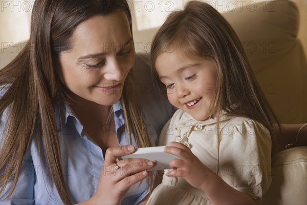 Chilean mother showing cell phone to daughter