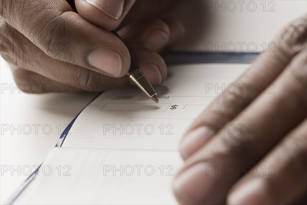 Mixed race man writing a check