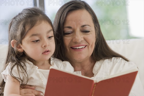 Hispanic grandmother reading to granddaughter