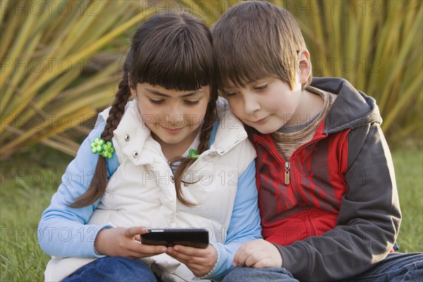 Chilean brother and sister looking at cell phone