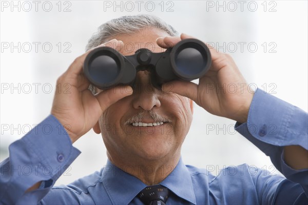 Hispanic businessman using binoculars