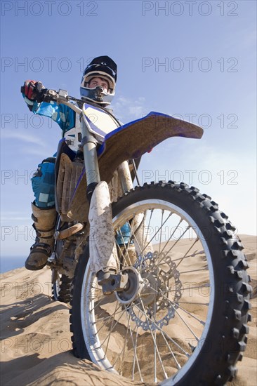 Chilean teenager riding motorcycle on sand dune