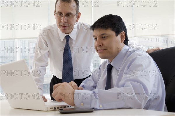 Hispanic businessman looking at laptop together