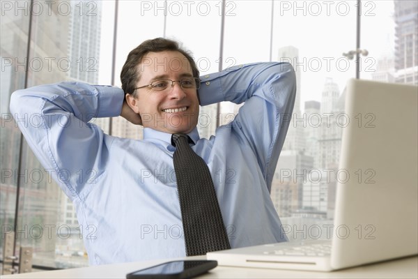 Caucasian businessman stretching at desk