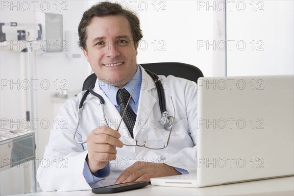 Caucasian doctor sitting at desk with laptop