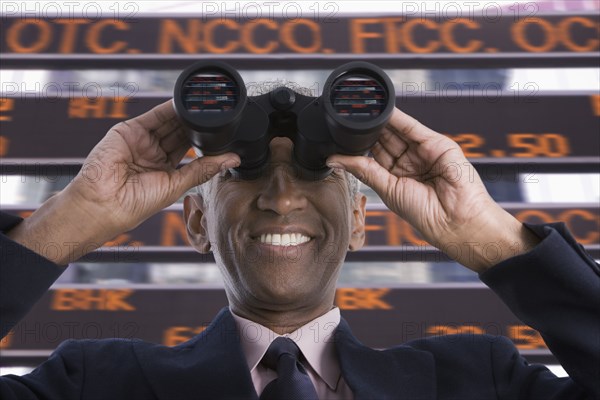 Smiling mixed race businessman using binoculars