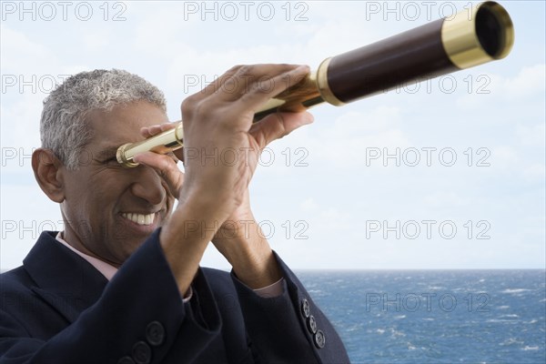 Mixed race businessman using telescope