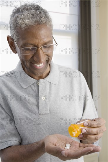 Mixed race man shaking pills from bottle