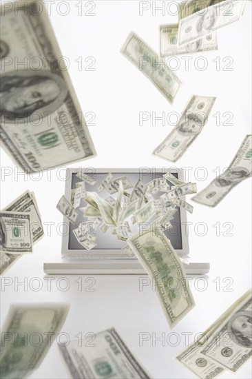 Dollar bills flying from laptop computer