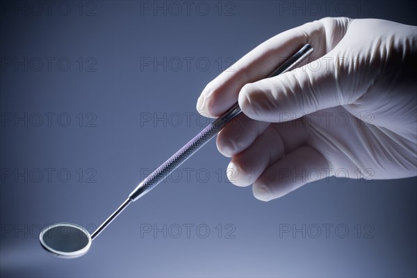 Close up of Hispanic dentist holding mirror