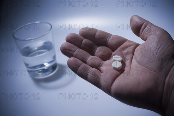 Close up of pills in Hispanic man's hand