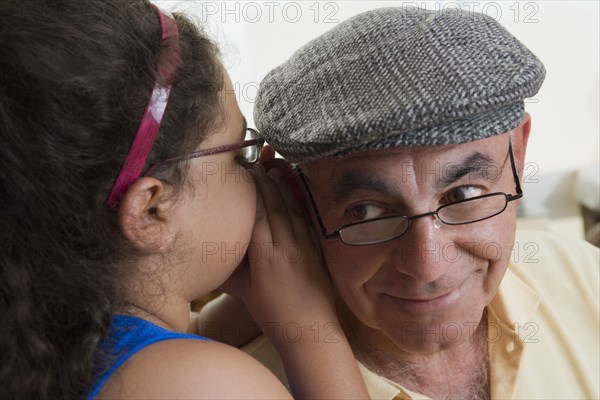 Hispanic girl whispering to grandfather