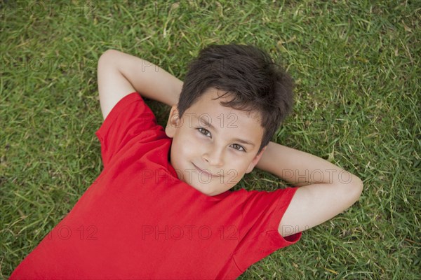 Hispanic boy laying in grass