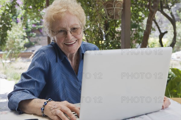 Older Hispanic woman using laptop outdoors