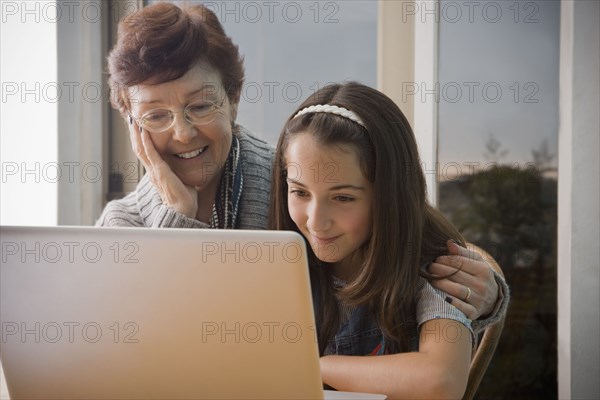 Older Hispanic woman using laptop with granddaughter