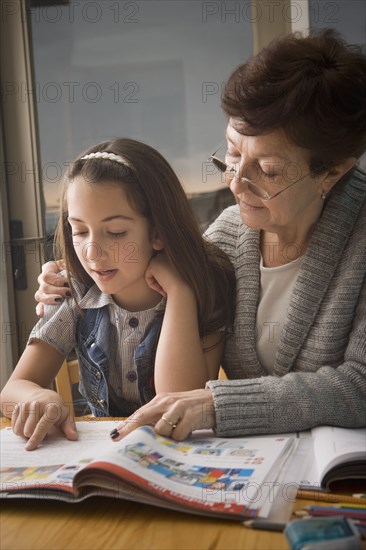 Older Hispanic woman reading with granddaughter