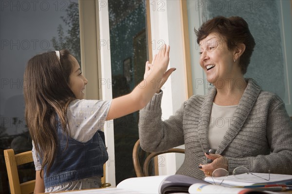 Older Hispanic woman high-fiving granddaughter