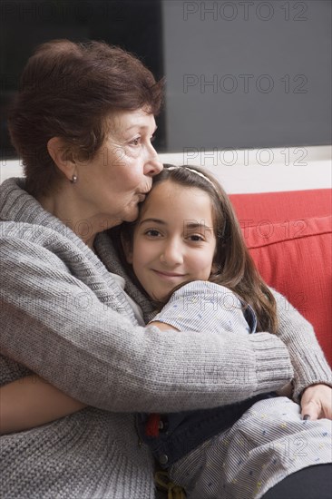 Older Hispanic woman hugging granddaughter