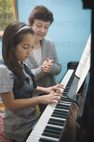 Older Hispanic woman playing music with granddaughter