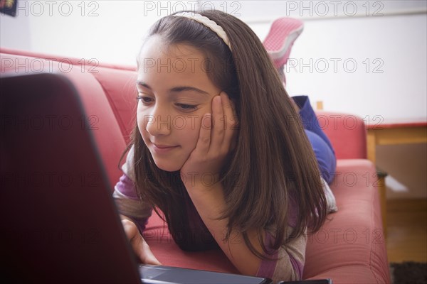 Hispanic girl using laptop on sofa