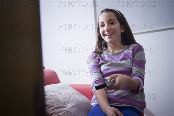 Hispanic girl watching television on sofa