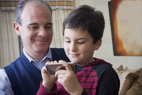 Hispanic father and son using cell phone