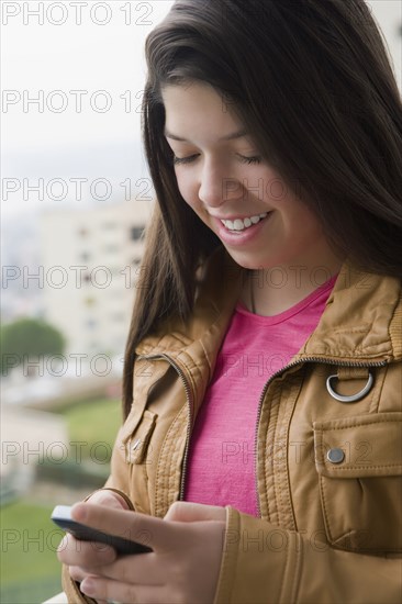 Hispanic girl using cell phone outdoors