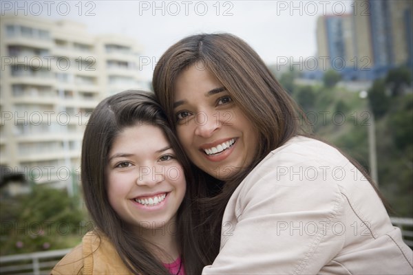 Hispanic mother and daughter smiling outdoors