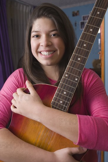 Hispanic girl hugging guitar