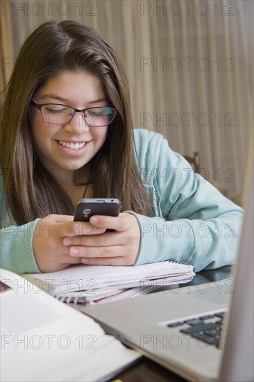 Hispanic girl using cell phone at laptop