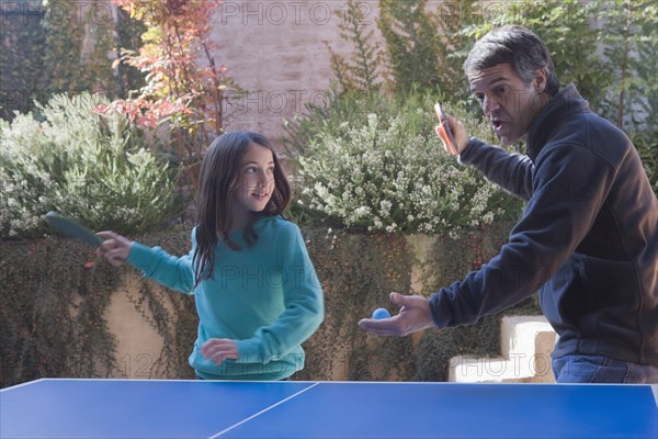 Hispanic father and daughter playing ping pong