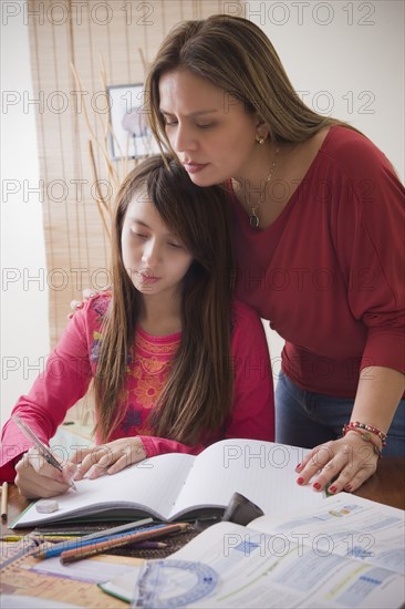 Hispanic mother helping daughter with homework