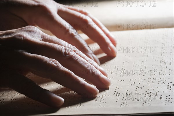 Close up of Hispanic person reading Braille