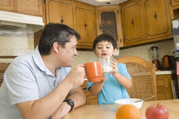 Hispanic father and son toasting each other