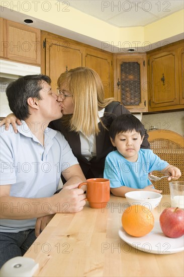 Hispanic couple kissing in kitchen