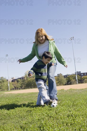 Hispanic mother and son playing soccer outdoors
