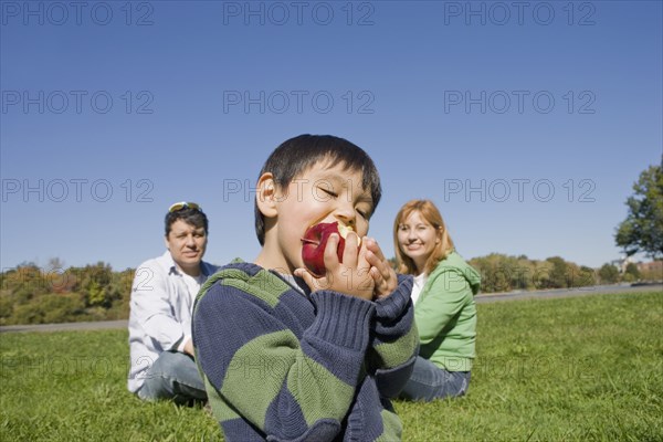 Hispanic boy eating fruit outdoors