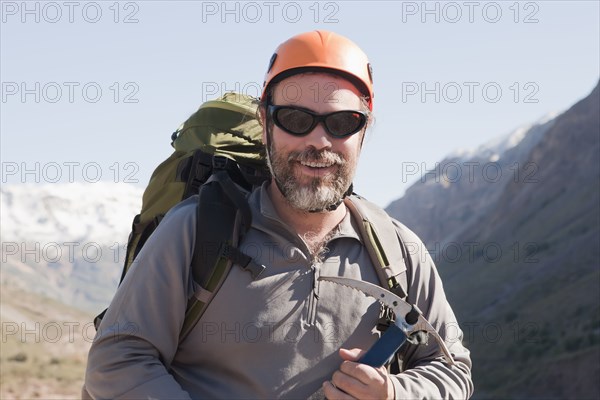 Hispanic hiker carrying ice ax in mountains