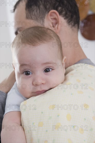 Hispanic father holding baby boy on his shoulder