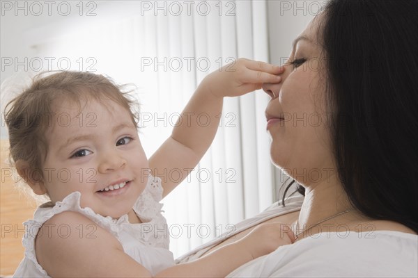 Hispanic baby girl touching mother's nose