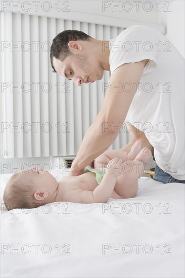 Hispanic father changing baby boy's diaper